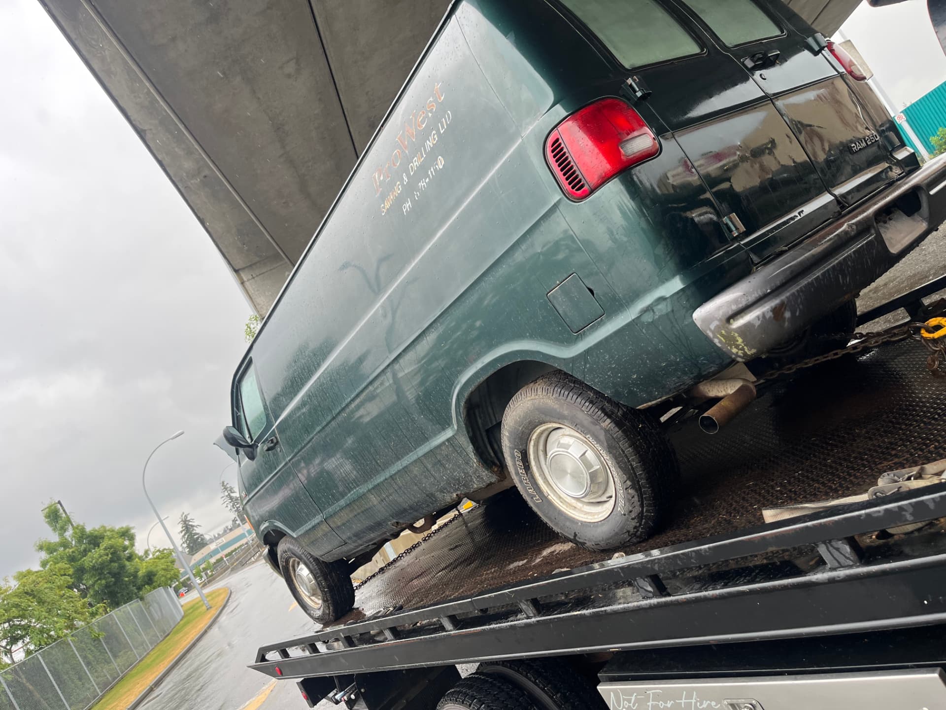 Dark green Dodge Ram 2500 work van loaded on a flat deck for scrap removal in Mission, BC