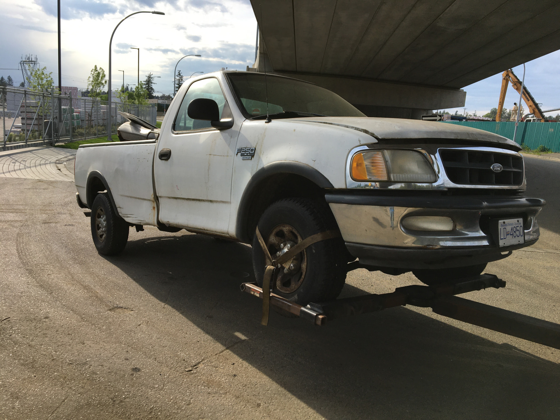 White Ford F-250 pickup secured on a tow truck wheel lift for junk truck removal in Mission, BC